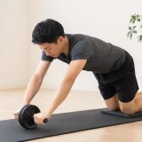 自宅で膝コロの腹筋ローラーを正しいフォームで行う男性