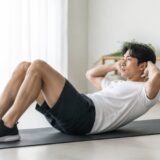 自宅で正しいフォームのクランチを行う男性