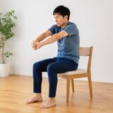 椅子に座って背中をゆっくり伸ばす男性