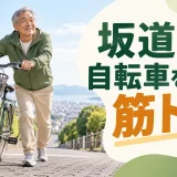 坂道で自転車を身体の横に近づけて押す中高年男性