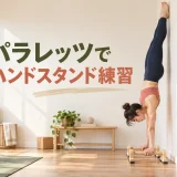 壁を使ってパラレッツのハンドスタンドを練習する女性