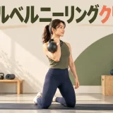 膝立ちでケトルベルをラックへ収める人物
